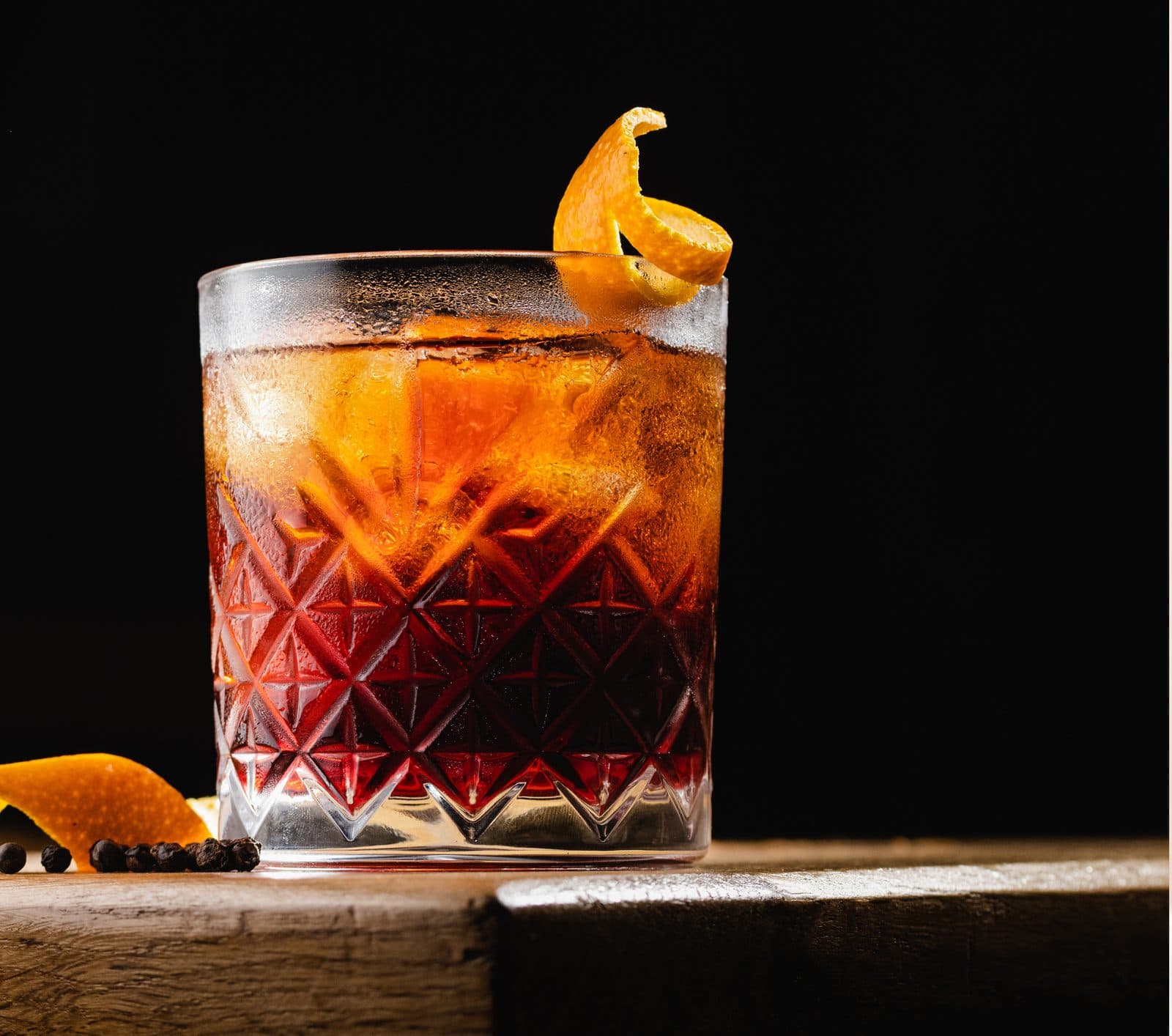 An Old Fashioned in a cut-crystal tumbler with a flamed orange twist